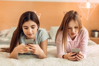 Dos chicas utilizan sus teléfonos móviles.