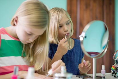 Young sisters playing dress up and using lip gloss