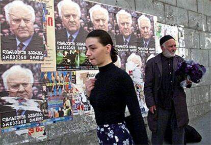 Una joven camina junto a una pared, con carteles electorales, en el año 2000 en Tbilisi, Georgia.