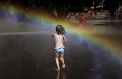 Una niña corre hacia el arco iris en un parque de Madrid. 