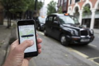 Un usuario utiliza la aplicaci&oacute;n de Uber frente a una parada de taxis de Londres. 