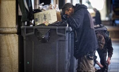 Dos personas buscan comida en un contenedor en Barcelona.