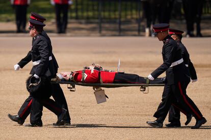 A trombone player of the military band is carried out on a stretcher after a faint during the Colonel's Review