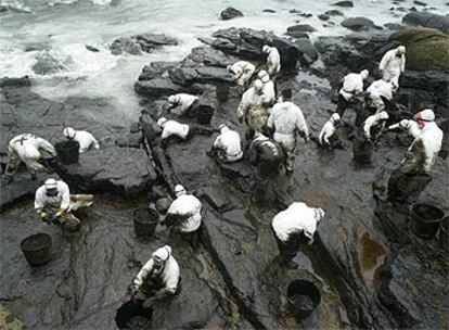 Decenas de voluntarios ayudaron ayer a limpiar de fuel la playa de Coído, en Muxía (A Coruña).