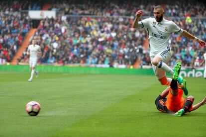 Benzema salta sobre un jugador del Valencia para hacerse con el balón.