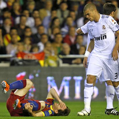 Messi, en el suelo, se lamenta delante de Pepe. El portugués ha sido el primer amonestado del partido por una falta sobre Pedro.