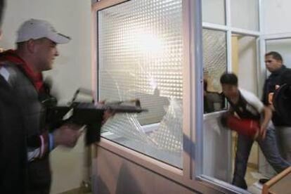 Militantes de Al Fatah utilizan rifles para romper ventanas del Parlamento palestino.