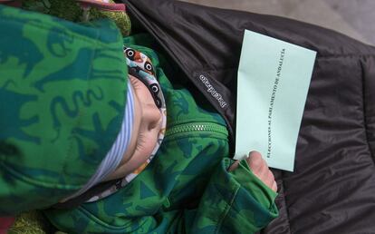 Un niño lleva una papeleta en un colegio electoral de Jaén.