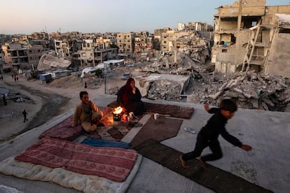 Miembros de una familia palestina se reúnen alrededor de una hoguera en el techo de su casa destruida en Jan Yunis, sur de la Franja de Gaza, el pasado 30 de septiembre