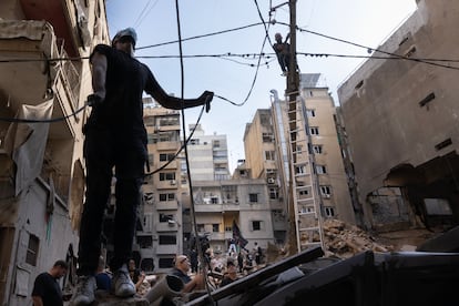 Dos hombres trabajan en las líneas eléctricas tras un ataque nocturno israelí en Beirut, el viernes.