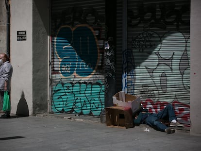 Una persona sin hogar duerme en la plaza del Pedró, en Barcelona.