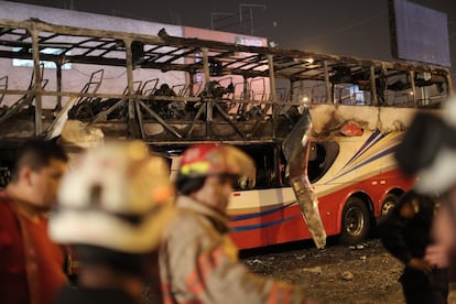 Um grupo ficou preso na escada que ligava os dois andares e morreu por sufocamento. Na imagem, um grupo de pessoas na frente dos restos do ônibus queimado.