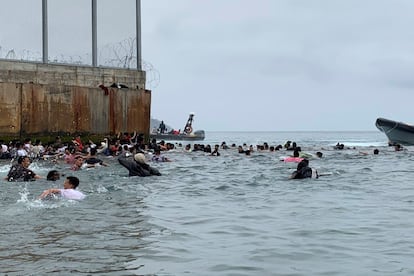 Um grupo de pessoas tentam chegar nadando desde a praia da localidade de Fnideq (Castillejos, Marrocos) para um dos quebra-mares de Ceuta, nesta terça-feira.