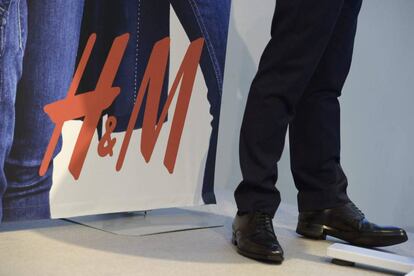 Un hombre al lado de un cartel de H&amp;M en una de sus tiendas