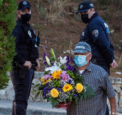 Un hombre pasa junto a dos policías, antes de visitar la tumba de sus familiares en el cementerio de Andrax, este domingo.