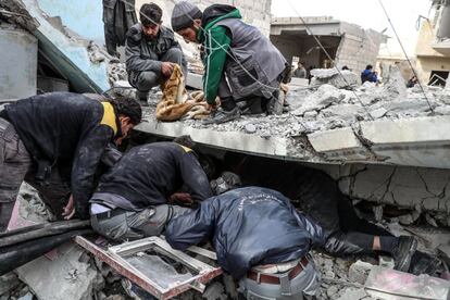 Voluntarios de los Cascos Blancos buscan supervivientes bajo los escombros tras un ataque aéreo en Douma (Siria).