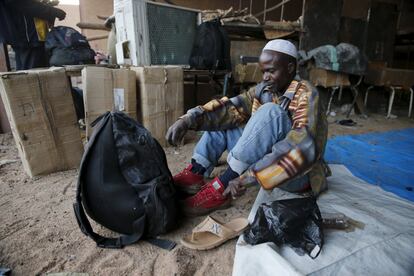 Un migrante se cambia de zapatos mientras se prepara para subir a un camión en la ciudad de Agadez.