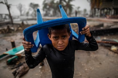 El 17 de noviembre de 2020, en Bilwi (Nicaragua), un niño se protege de la fuerte lluvia con una silla de plástico, parado en el lugar donde solía estar su casa, que quedó destruida tras el paso del huracán Iota.
