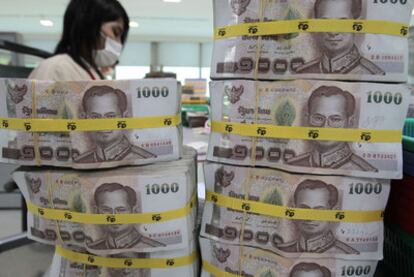 Una empleada cuenta billetes en un banco de Bangkok .