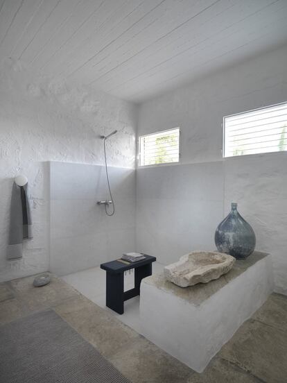 Como el resto de la casa, el baño combina mármol blanco, travertino y muros de piedra. Aquí las repisas son utilizadas como estantes. 
