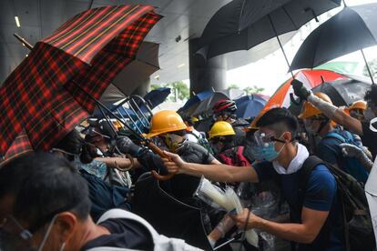 Los manifestantes se protegen con paraguas y mascarillas en los choques contra la policía, este miércoles en Hong Kong. Los manifestantes aseguran que con el proyecto de ley peligra el principio “un país, dos sistemas” que otorga al territorio autónomo derechos y libertades desconocidos en la China continental y que el Gobierno central prometió respetar durante 50 años en 1997, cuando el Reino Unido devolvió la excolonia a la soberanía china.