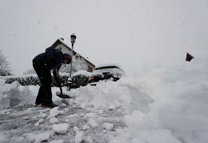 Un vecino de la localidad de Espinal, Navarra, intenta limpiar su coche de nieve.
