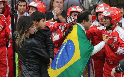 El brasileño Felipe Massa, del equipo Williams, lleva la bandera de su país sobre sus hombros, seguido por su esposa e hijo, es recibido por los integrantes del equipo Ferrari, al retirarse del GP de Brasil por problemas del coche, en el circuito de Interlagos.