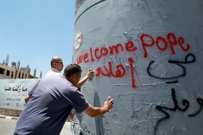 Dos hombres palestinos escriben con aerosol mensajes de bienvenida al Papa en una torre de vigilancia del ej&eacute;rcito israel&iacute; en Cisjordania. 