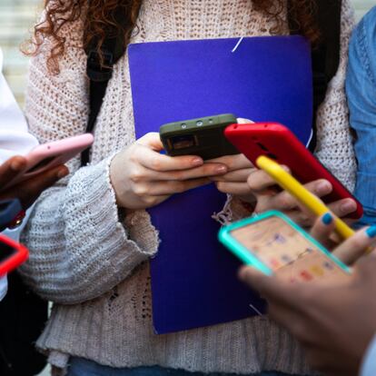 Close up of young college students hands holding mobile phones. Teenagers addicted to smartphones and technology. Group of friends sharing content on social media. Technology concept.