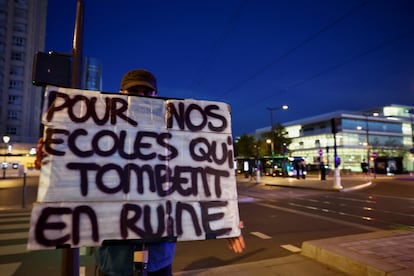 Una persona sostiene una pancarta que dice 'Por nuestras escuelas que se caen a pedazos', durante una manifestación del movimiento 'Bloqueemos todo' en Porte d’Aubervilliers, París.