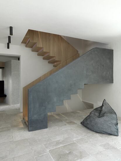 Una escalera escultórica de roble y hormigón ideada por los arquitectos BergmeisterWolf conduce al dormitorio.