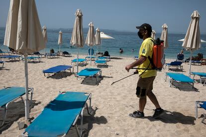 Un hombre desinfecta las hamacas de una playa próxima a Atenas, este sábado. 