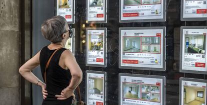 Una mujer revisa los carteles de una inmobiliaria en Barcelona.