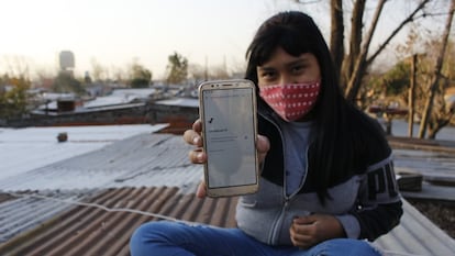 La hija de Soledad Delgado sostiene el único celular que tiene la familia para conectarse en Villa Fátima, en Buenos Aires (Argentina).