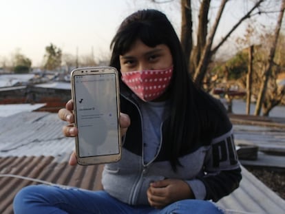 La hija de Soledad Delgado sostiene el único celular que tiene la familia para conectarse en Villa Fátima, en Buenos Aires (Argentina).