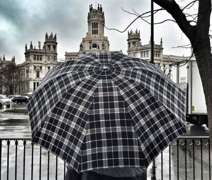 Una persona con un paraguas en la madrileña Plaza de Cibeles, en un día de lluvia.