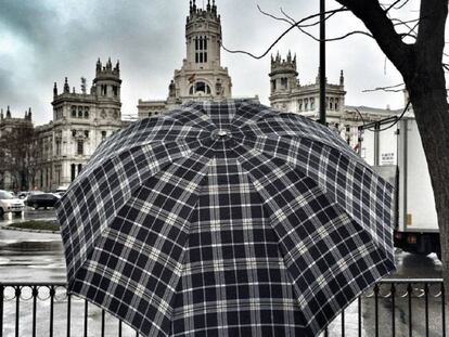 Una persona con un paraguas en la madrileña Plaza de Cibeles, en un día de lluvia.