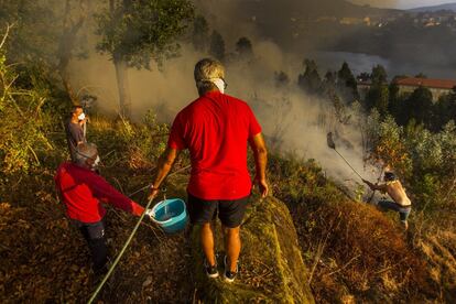 Los incendios forestales de esta semana, a pesar de no alcanzar las dimensiones de los grandes fuegos de otros años en Galicia, tienen como común denominador que se han declarado en terrenos próximos a núcleos habitados y han obligado a los desalojos de casas e incluso de un polígono industrial (Vilagarcía). En la imagen, vecinos de la parroquia de Acevedo (Pontevedra) intentan apagar el fuego con cubos de agua, el 10 de agosto.