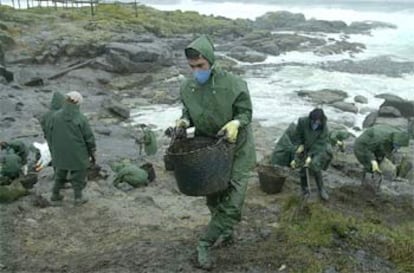 Varios voluntarios recogen restos de fuel en una zona de la costa de la localidad coruñesa de Muxía.