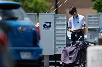 A mailman wears a face mask while completing his route on May 23, 2020, in downtown Littleton, Colo.