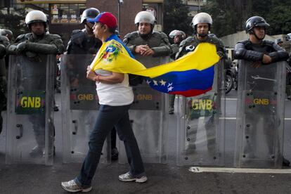 Una mujer camina frente a miembros de la Guardia Nacional Bolivariana (GNB) durante una protesta contra el gobierno de Venezuela, 17 de febrero de 2014, en el sector Altamira de Caracas (Venezuela).