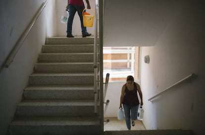 Yelitza Izalla y Carlos Guerra suben recipientes llenos de agua a su apartamento.