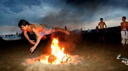 Un joven salta sobre una hoguera en la playa de la Malvarosa durante la Noche de San Juan.