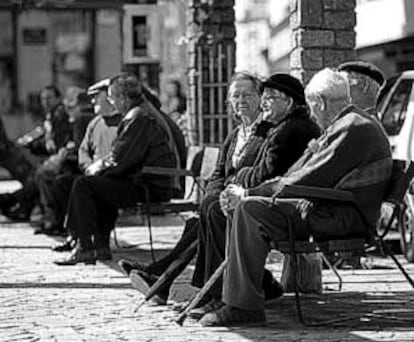 Varios ancianos toman el sol en los bancos de la plaza del pueblo de Ponteareas (Pontevedra).