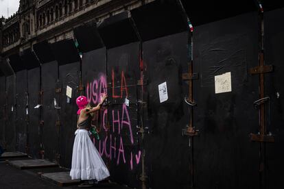 Una mujer pinta una consigna sobre las barricadas que fueron colocadas alrededor de Palacio Nacional, en el Centro Histórico de Ciudad de México, durante las protestas para exigir aborto legal y seguro, el 28 de septiembre.