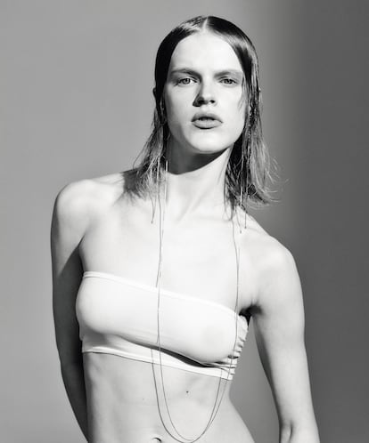 Top en gasa y pendientes en forma de cadena que se alargan desde el cuello, ambos de ALAÏA.