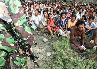 Un soldado indonesio vigila a un grupo de refugiados de Aceh tras un enfrentamiento con la guerrilla.