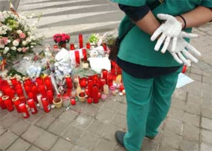 Una mujer con las manos pintadas de blanco frente a las ofrendas de flores y las velas encendidas colocadas en las inmediaciones de la Estacin de tren de Santa Eugenia en se?al de duelo por los atentados perpetrados ayer en Madrid.