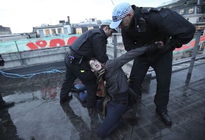 Policías detienen a un manifestante que estaba encaramado a un edificio.