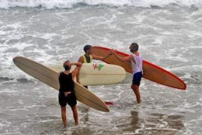 Tres surfistas con tablas 'longboards' en la playa de Salinas, en Asturias.